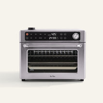 A stainless steel countertop oven with digital controls, a clear front door, and a visible wire rack inside, set against a plain background.