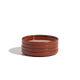 A stack of four round, shallow, reddish-brown ceramic plates on a plain white background.