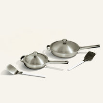 Set of stainless steel cookware including pots, pans, and spatulas on a white background