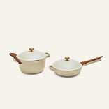 The Cookware Duo features two cream-colored pots with lids—a round Dutch oven with a wooden spoon and a skillet with chopsticks—perfect as a compact alternative to an 18-piece set and ideal for any kitchen.